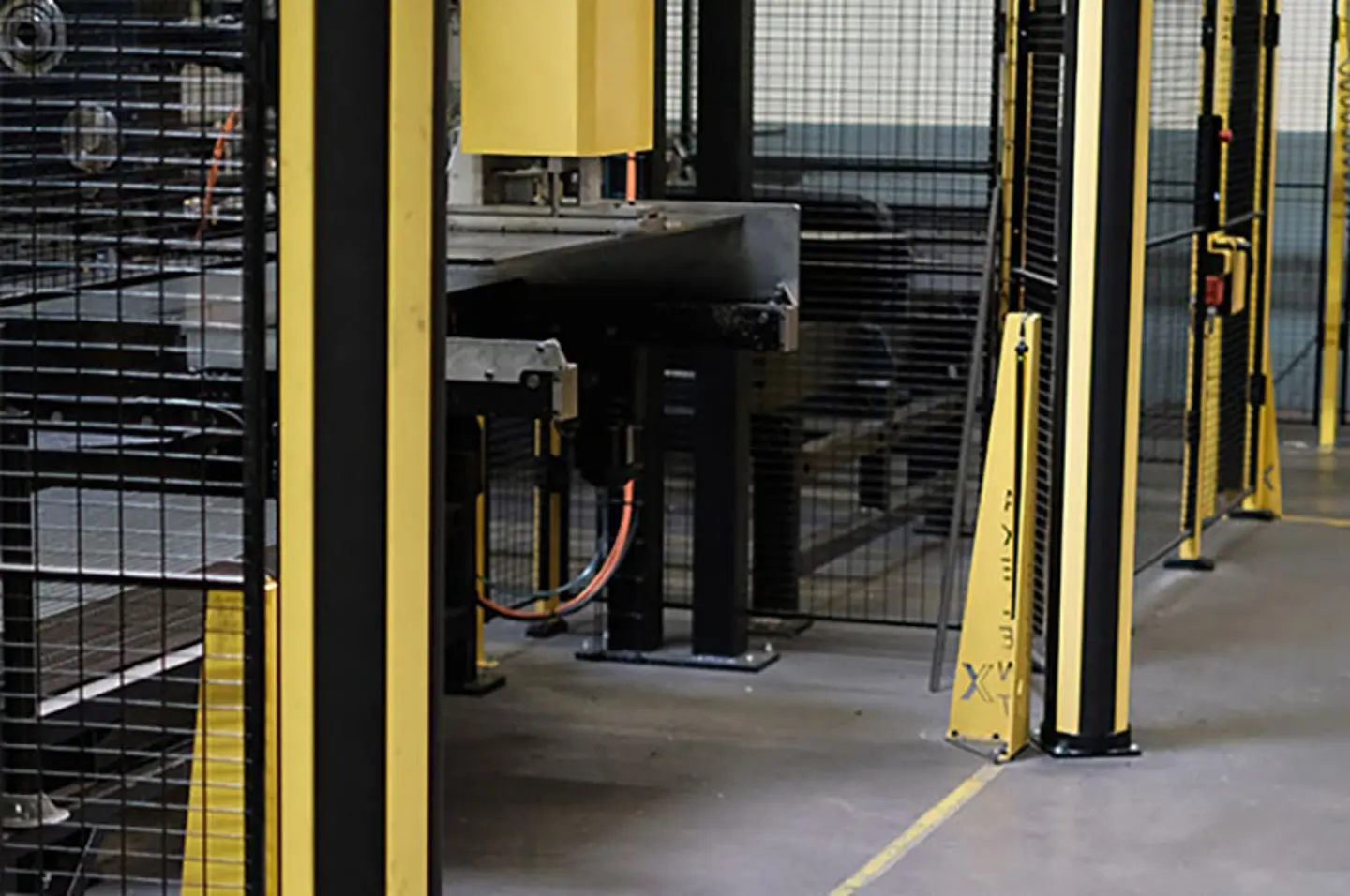 Barriere di sicurezza e protezioni macchine in magazzino a tutela dei percorsi pedonali intorno a nastri trasportatori automatizzati e sistemi robotici.