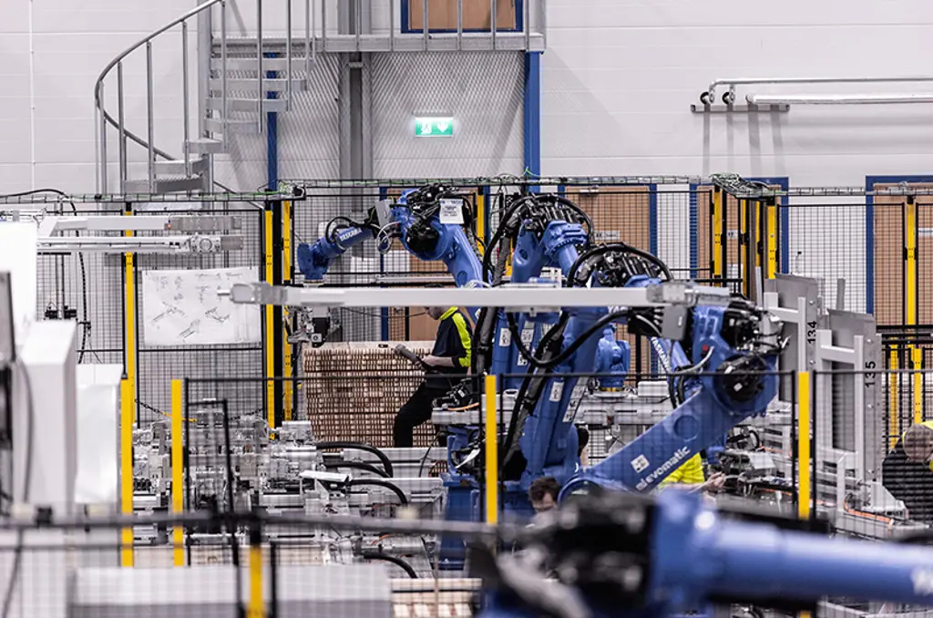 Braccia robotiche che pallettizzano scatole all’interno di una cella automatizzata protetta.