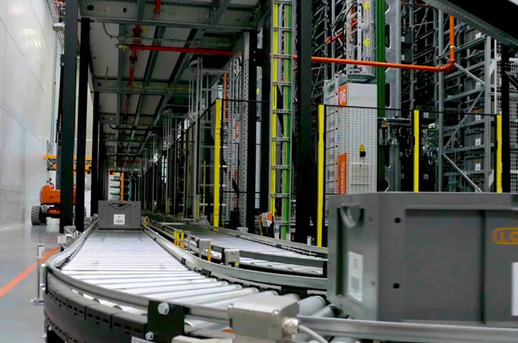 Attrezzature di smistamento automatizzate per magazzino con linea di trasporto e recinzioni di sicurezza per una movimentazione dei materiali sicura ed efficiente.