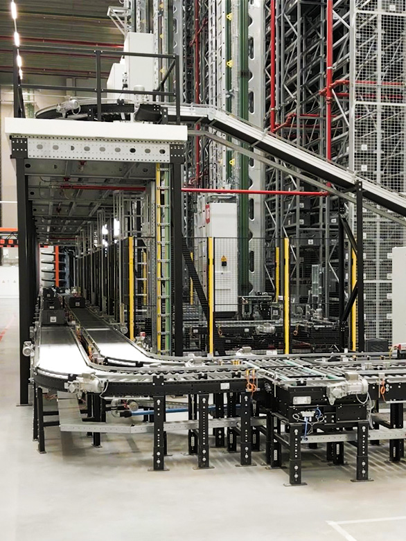 Sistema automatizzato a rulli e a nastro in un magazzino, utilizzato per il trasporto di cassette e contenitori.