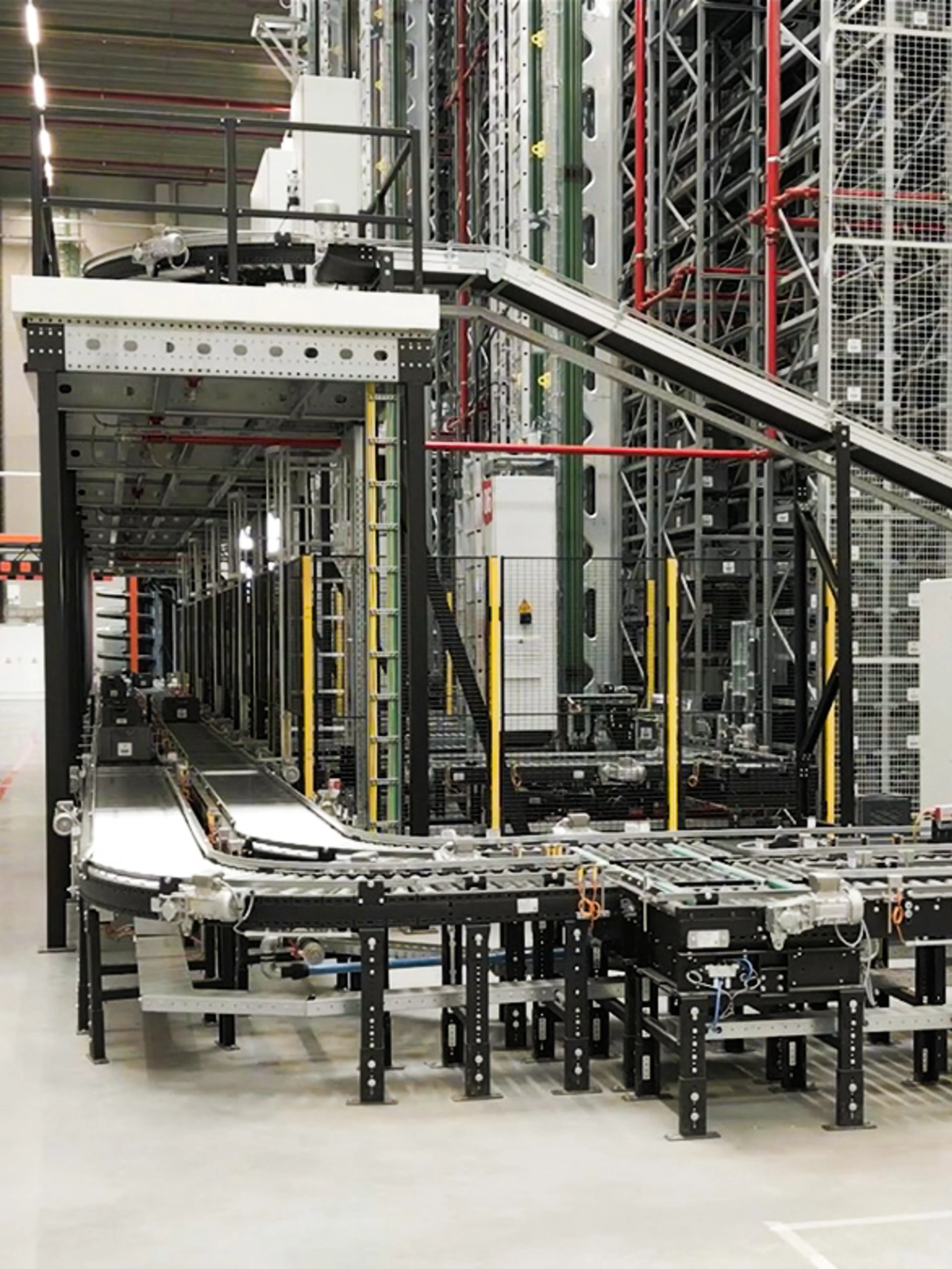 Sistema automatizzato a rulli e a nastro in un magazzino, utilizzato per il trasporto di cassette e contenitori.