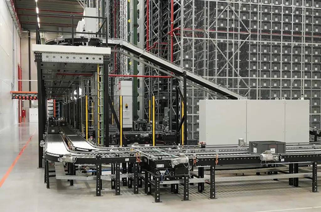 Sistema automatizzato a rulli e nastri trasportatori in un magazzino, utilizzato per il trasporto di cassette e contenitori.