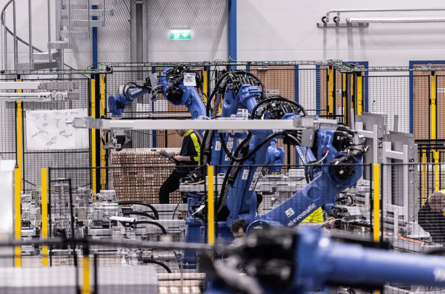 Bracci robotici industriali che pallettizzano merci all’interno di celle di automazione protette.